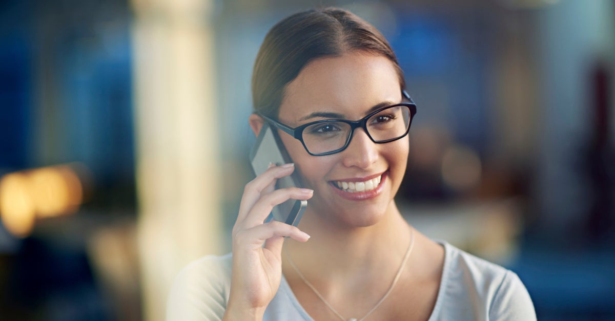mujer de negocios joven con gafas hablando por el teléfono móvil fondo desenfocado