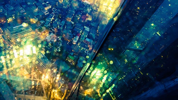 Vista de una gran ciudad iluminada por la noche observada desde lo alto a través de un cristal
