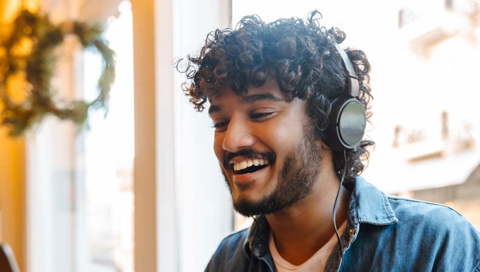 Young smiling handsome indian curly man holding videoconference 