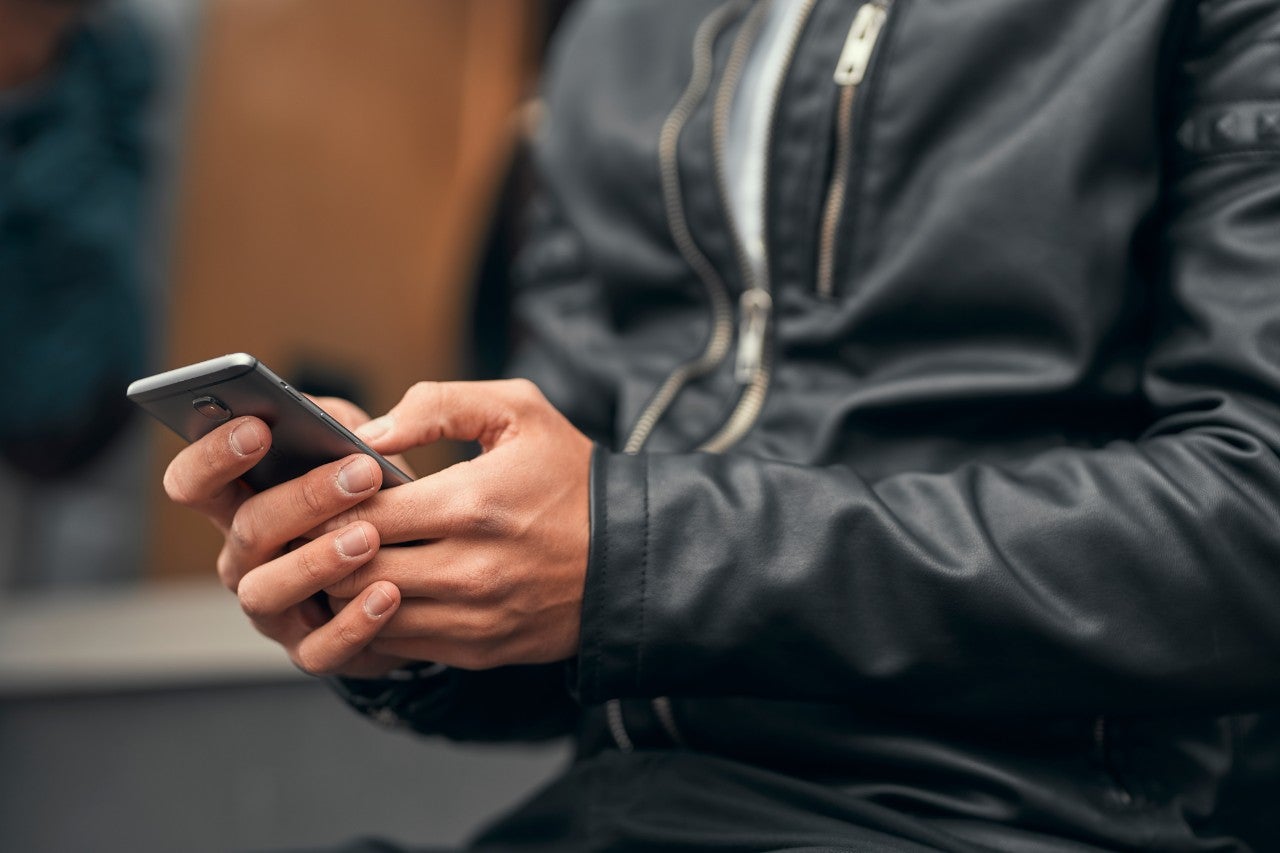 Close-up. The guy is holding a smartphone in his hands. Prints o