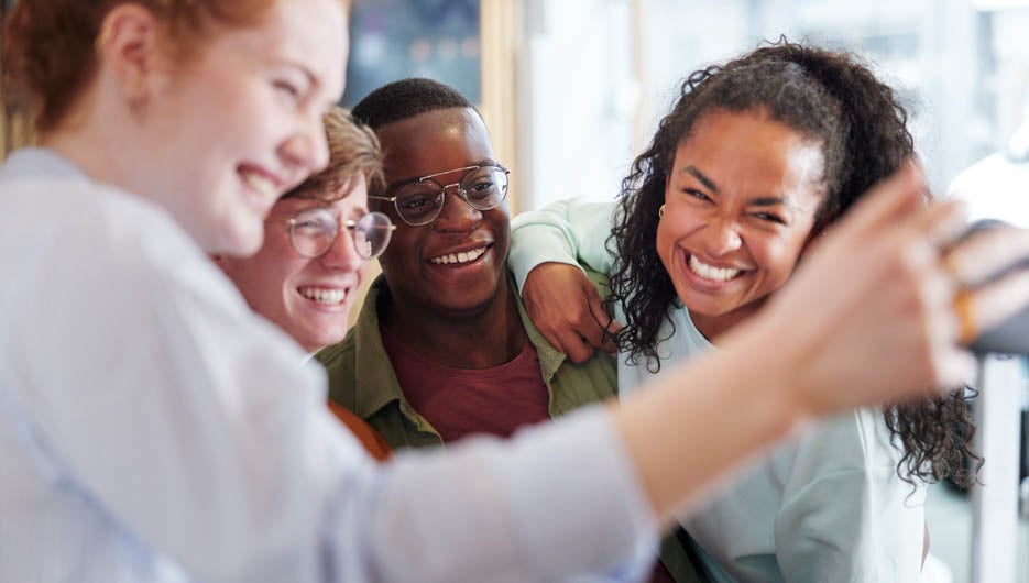 Laughing teens taking selfies together