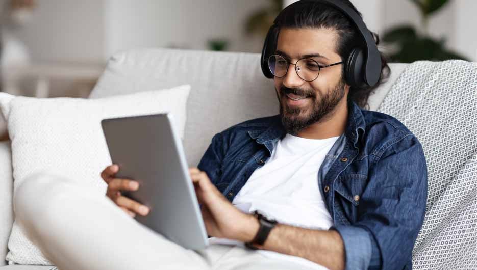 Handsome Indian Guy In Wireless Headphones Relaxing With Digital
