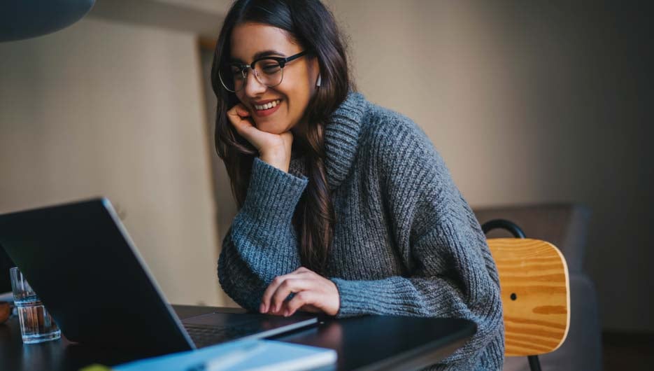 Happy smiling young woman using laptop computer device while wor